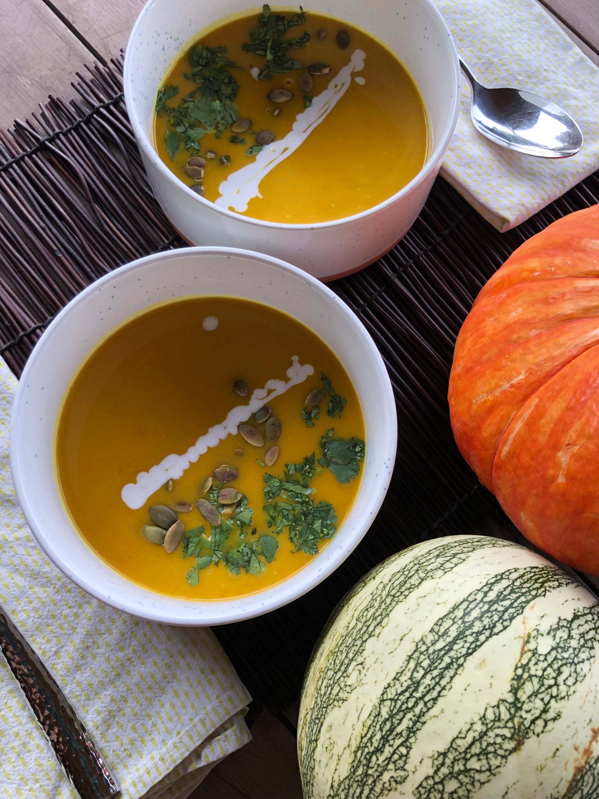 A warm bowl of creamy pumpkin soup garnished with a swirl of coconut milk, a drizzle of golden Manuka honey, toasted pepitas, and a crack of black pepper—an inviting go-to fall soup with rich orange color and smooth texture.
