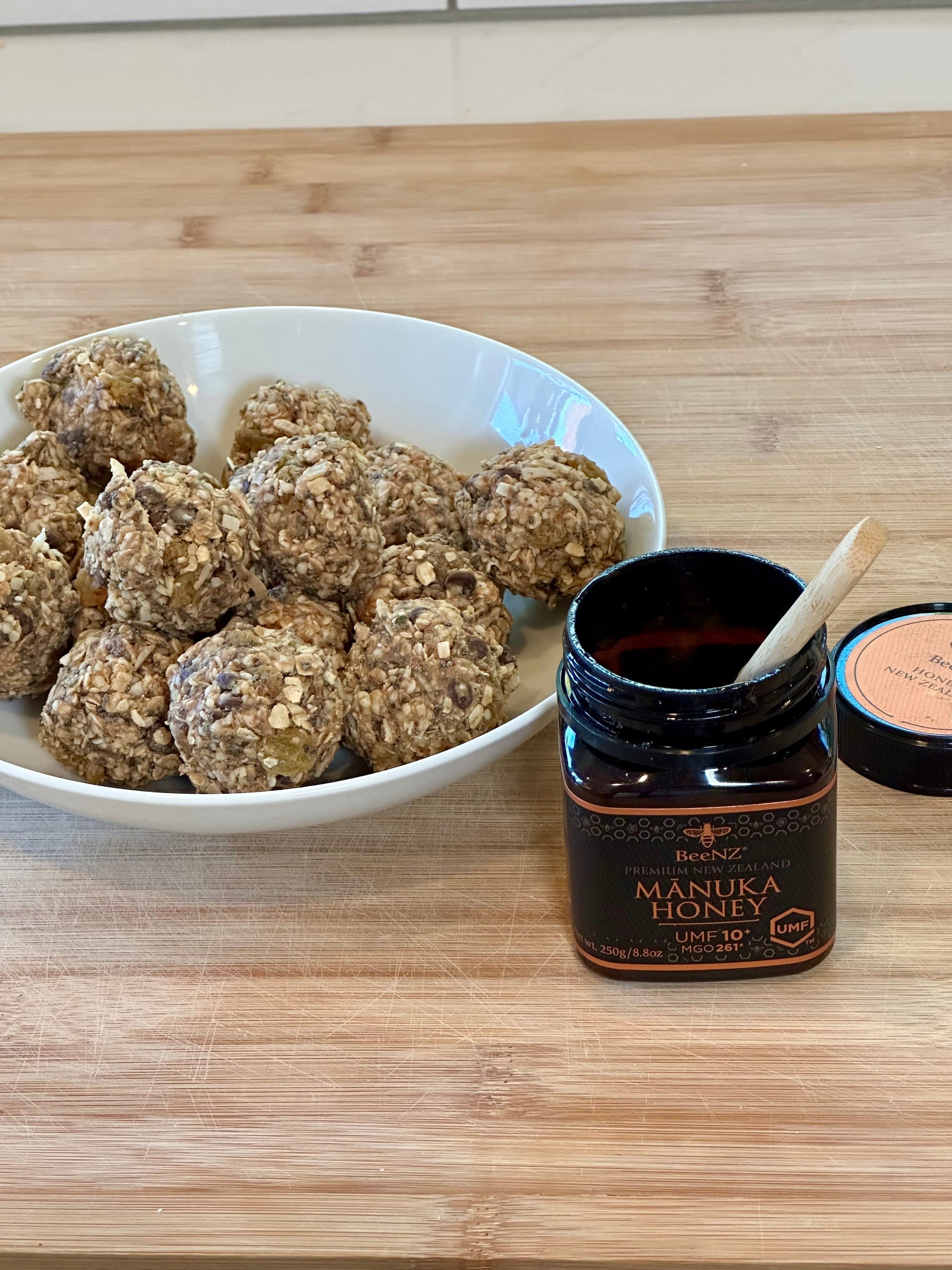 Easy-to-make back-to-school protein balls made with BeeNZ Mānuka and Kānuka honey, shown on a countertop with wholesome ingredients like oats and seeds—perfect for smart snacking during study time.